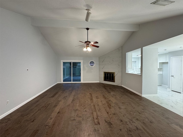 unfurnished living room with a textured ceiling, ceiling fan, wood-type flooring, a fireplace, and vaulted ceiling with beams