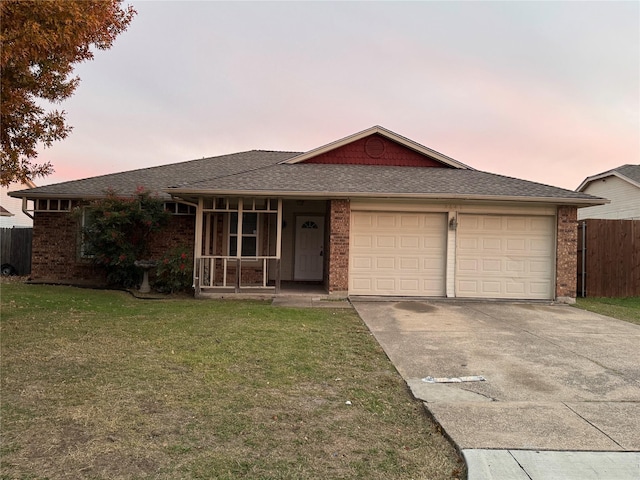 ranch-style home featuring a garage and a lawn