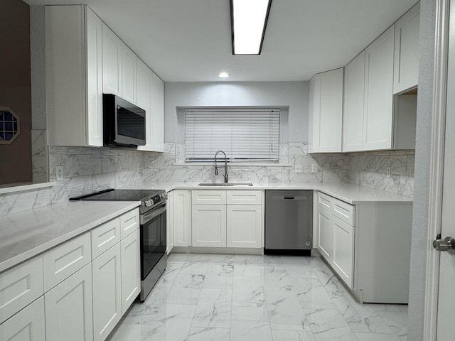 kitchen with white cabinetry, sink, light stone counters, and appliances with stainless steel finishes