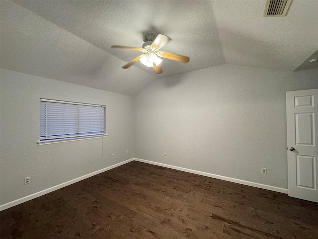 spare room with a textured ceiling, lofted ceiling, ceiling fan, and dark wood-type flooring