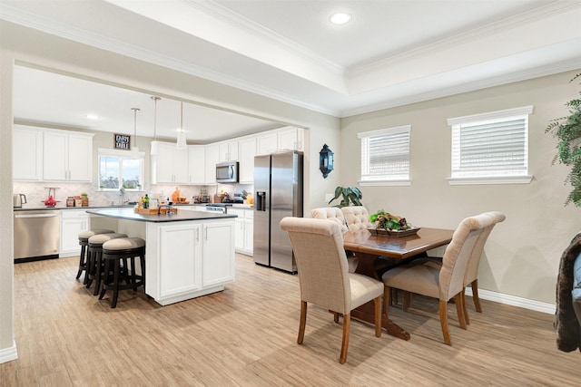 dining space with crown molding, sink, and light hardwood / wood-style floors