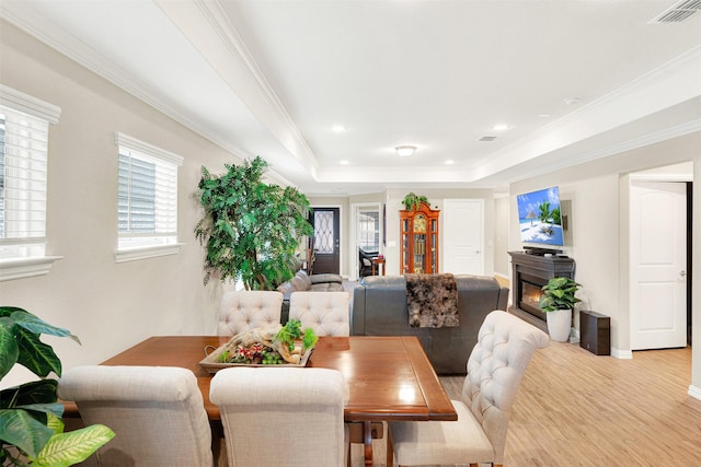 dining room featuring a tray ceiling, light hardwood / wood-style flooring, and ornamental molding