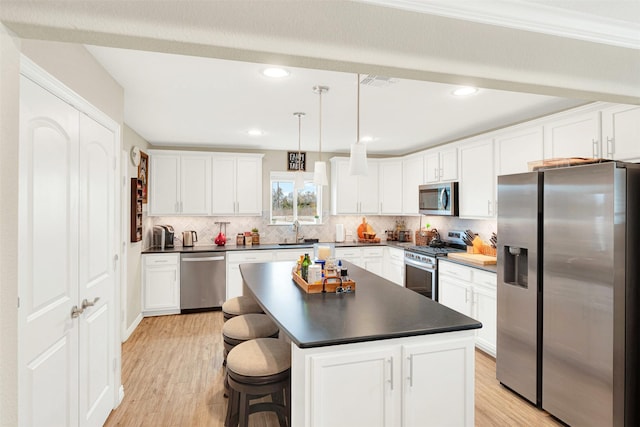 kitchen featuring pendant lighting, a center island, sink, light wood-type flooring, and stainless steel appliances