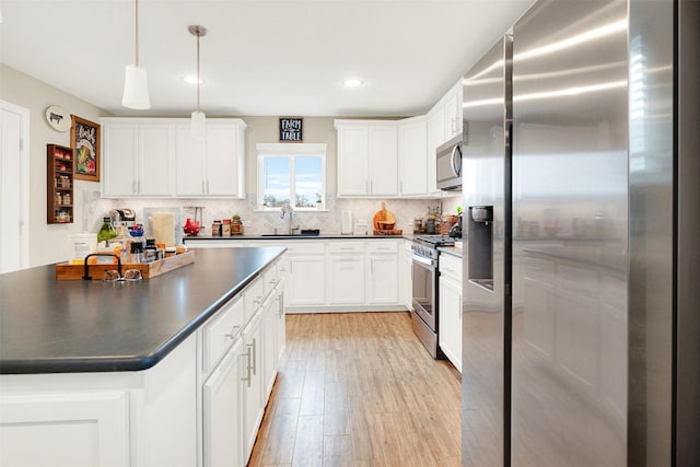 kitchen featuring stainless steel appliances, sink, decorative light fixtures, light hardwood / wood-style floors, and white cabinetry