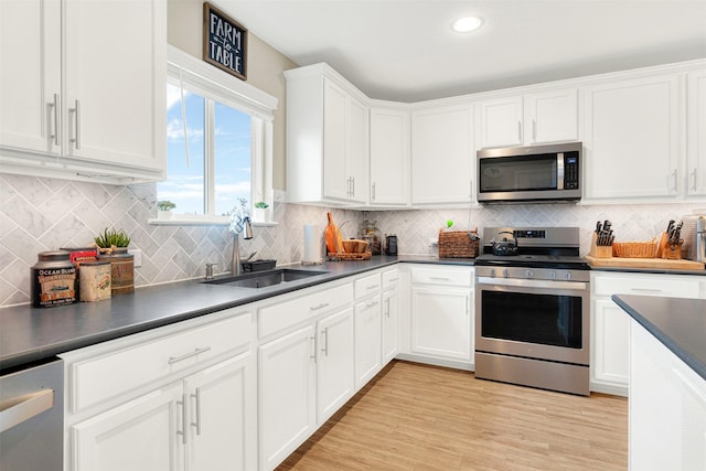 kitchen featuring white cabinets, sink, light hardwood / wood-style flooring, tasteful backsplash, and stainless steel appliances