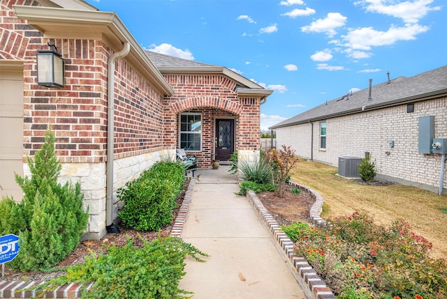 entrance to property featuring a yard and central AC unit