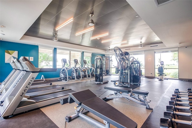 gym with a tray ceiling and ceiling fan