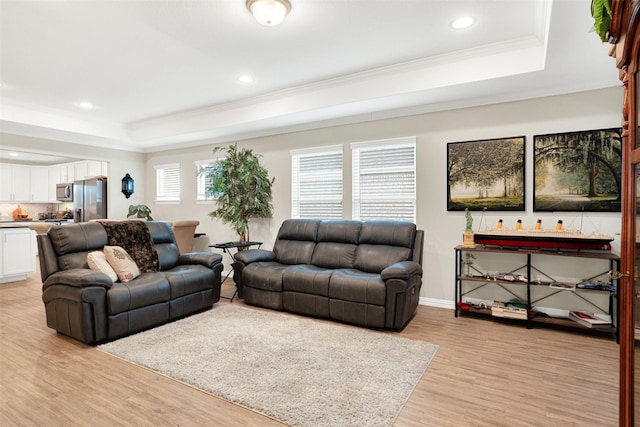 living room with a raised ceiling, light hardwood / wood-style flooring, and ornamental molding