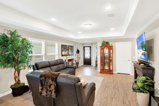 living room featuring light hardwood / wood-style floors, a tray ceiling, and crown molding