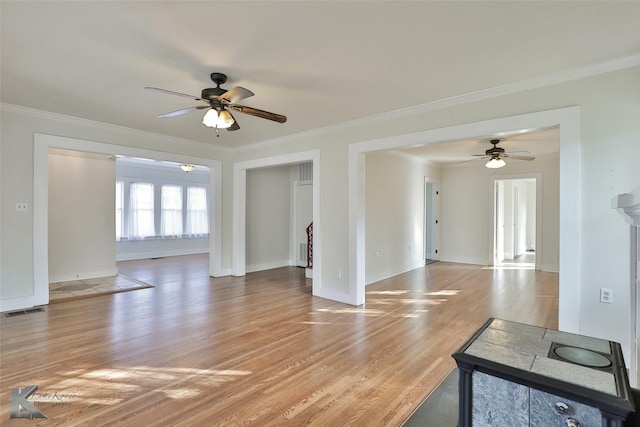 unfurnished living room featuring ceiling fan, ornamental molding, and light wood-type flooring