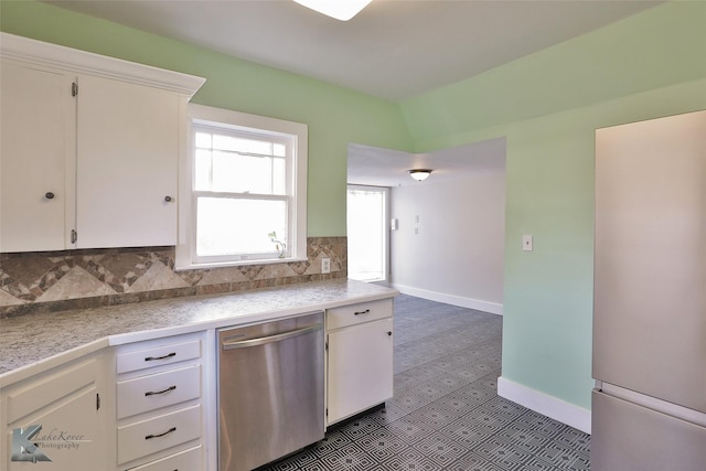 kitchen with tasteful backsplash, stainless steel dishwasher, dark tile patterned floors, white refrigerator, and white cabinetry