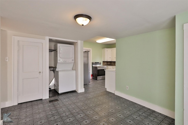 kitchen featuring stacked washer and dryer, white cabinets, and stainless steel range with electric cooktop