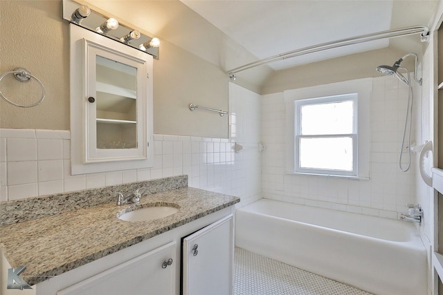 bathroom featuring tile walls, vanity, and tiled shower / bath combo