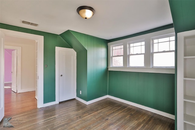 bonus room featuring dark hardwood / wood-style floors and wooden walls