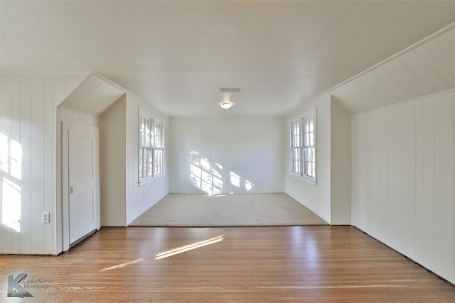 additional living space featuring hardwood / wood-style floors, vaulted ceiling, plenty of natural light, and wooden walls