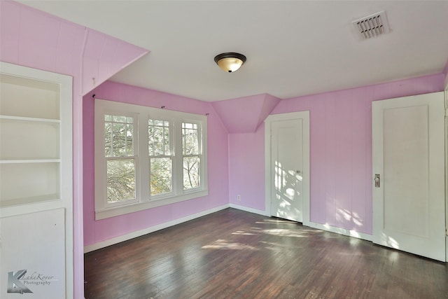 bonus room with built in shelves and dark hardwood / wood-style floors