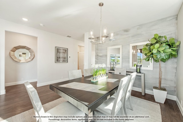 dining area featuring dark wood-type flooring and an inviting chandelier