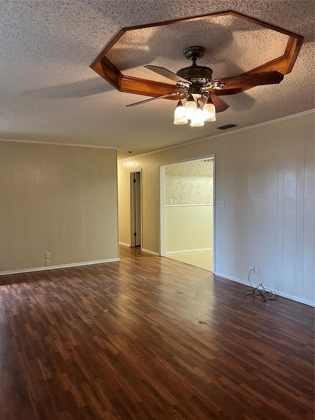 unfurnished room with wood walls, dark hardwood / wood-style floors, ceiling fan, and a textured ceiling