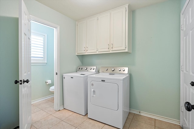 laundry area featuring cabinets, independent washer and dryer, and light tile patterned floors