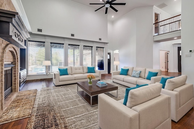 living room featuring hardwood / wood-style floors, ceiling fan, crown molding, and a high ceiling