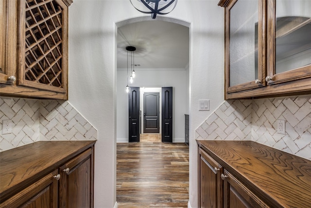 kitchen featuring dark hardwood / wood-style flooring, crown molding, hanging light fixtures, and tasteful backsplash