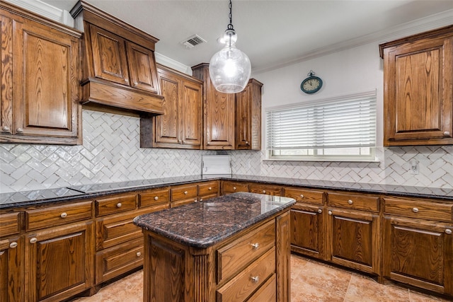 kitchen with crown molding, hanging light fixtures, dark stone countertops, tasteful backsplash, and a kitchen island