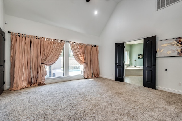 unfurnished bedroom featuring carpet flooring, ensuite bath, and high vaulted ceiling