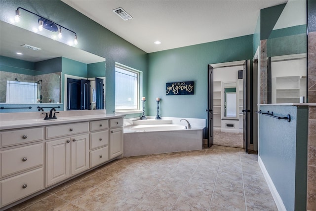 bathroom featuring plus walk in shower, tile patterned flooring, and vanity