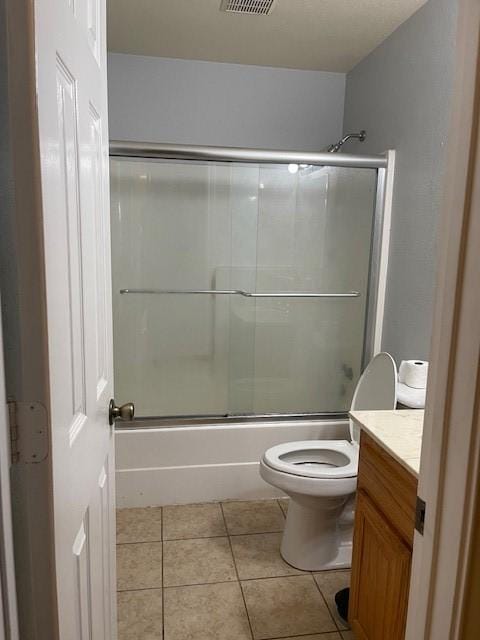 full bathroom featuring tile patterned flooring, vanity, combined bath / shower with glass door, and toilet