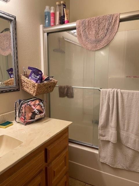 bathroom with enclosed tub / shower combo, vanity, and tile patterned flooring