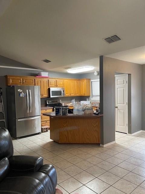 kitchen with appliances with stainless steel finishes, light tile patterned floors, and kitchen peninsula