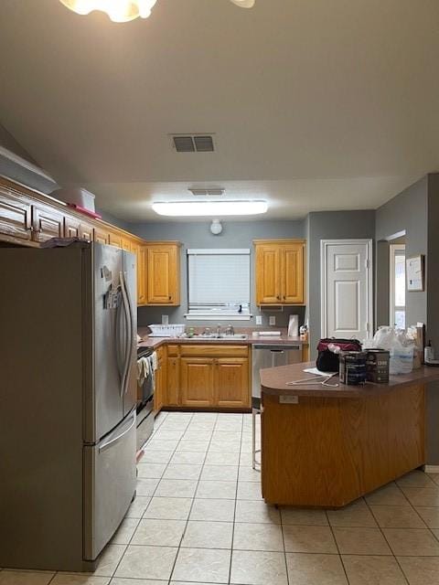 kitchen with light tile patterned floors, stainless steel appliances, sink, and kitchen peninsula