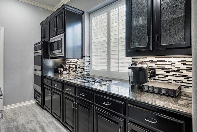 kitchen with decorative backsplash, stainless steel appliances, crown molding, and light hardwood / wood-style floors