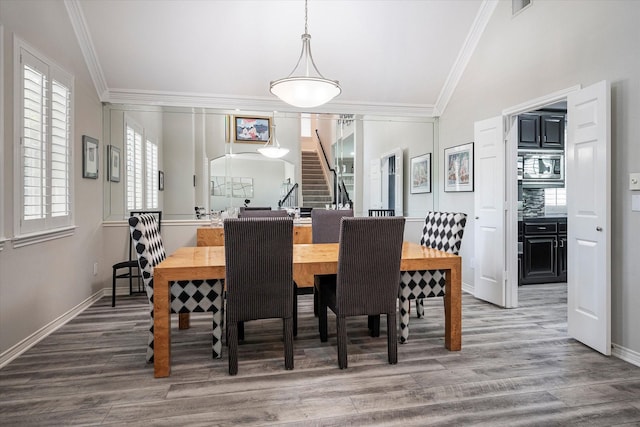 dining area featuring lofted ceiling, hardwood / wood-style flooring, and crown molding