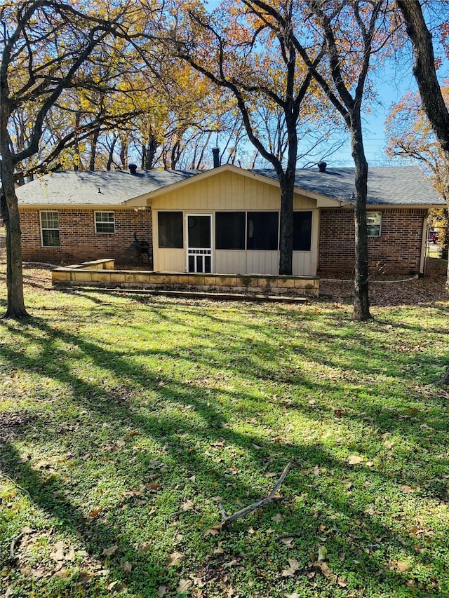 rear view of house with a sunroom and a lawn