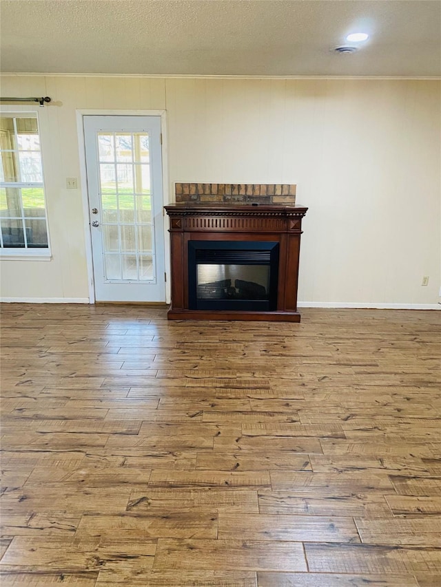 unfurnished living room featuring ornamental molding, a textured ceiling, and light wood-type flooring