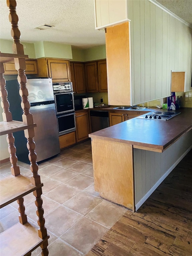 kitchen featuring a breakfast bar, kitchen peninsula, a textured ceiling, and stainless steel appliances