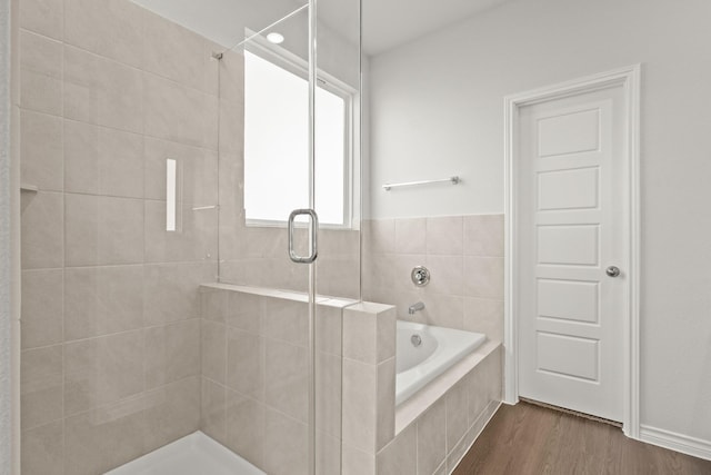 bathroom featuring wood-type flooring and shower with separate bathtub