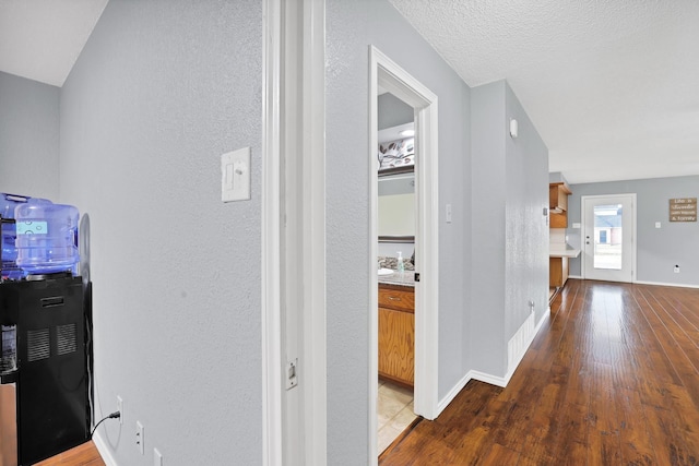 corridor with a textured ceiling and dark wood-type flooring