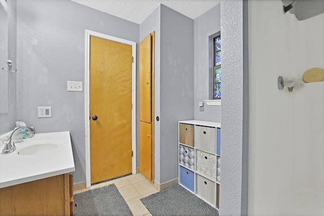 bathroom with tile patterned floors, vanity, and a textured ceiling