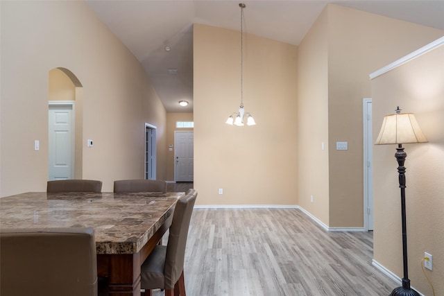 dining space featuring high vaulted ceiling, a notable chandelier, and light wood-type flooring