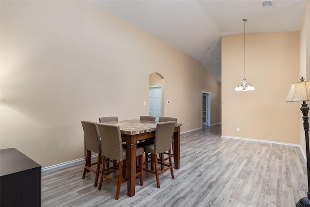 dining room featuring light hardwood / wood-style floors, high vaulted ceiling, and a notable chandelier