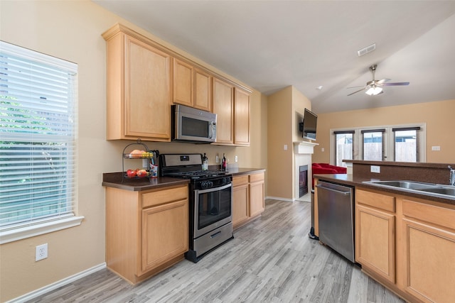 kitchen featuring sink, stainless steel appliances, light hardwood / wood-style flooring, lofted ceiling, and light brown cabinetry