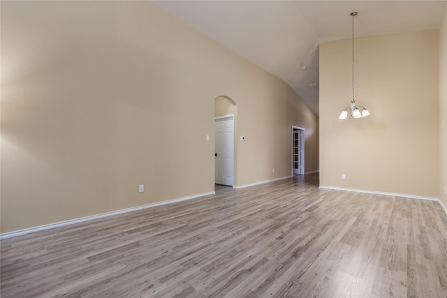 unfurnished living room with a notable chandelier, high vaulted ceiling, and light hardwood / wood-style flooring