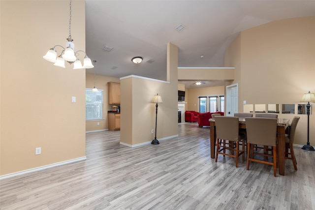 dining space with light hardwood / wood-style floors, vaulted ceiling, and a notable chandelier