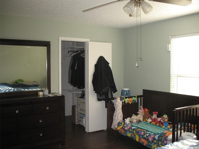 bedroom with ceiling fan, dark hardwood / wood-style floors, a textured ceiling, and multiple windows