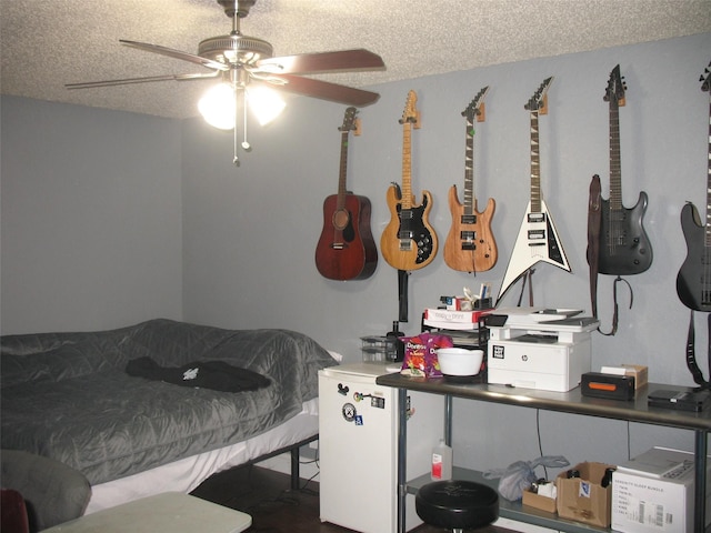 bedroom with a textured ceiling, white refrigerator, and ceiling fan