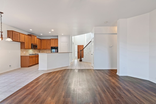 kitchen with decorative backsplash, light tile patterned floors, decorative light fixtures, a center island, and black oven