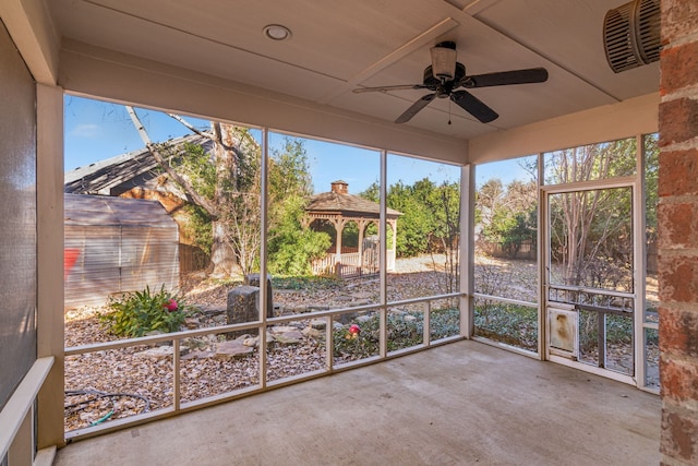 unfurnished sunroom featuring ceiling fan and a wealth of natural light