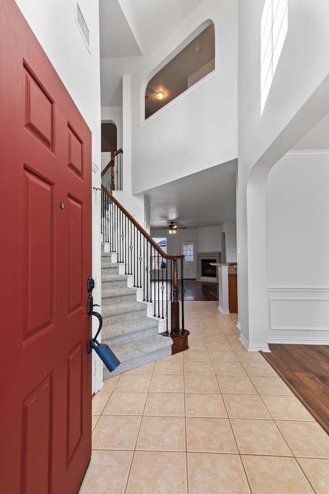 tiled entryway with a towering ceiling and ceiling fan